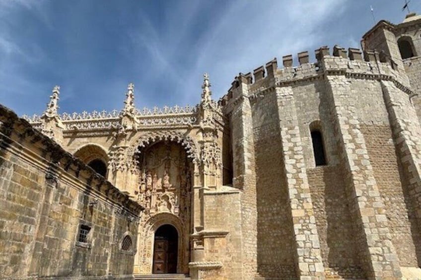 A historic stone building with ornate Gothic architecture, including a large arched doorway and a tower with battlements. 5