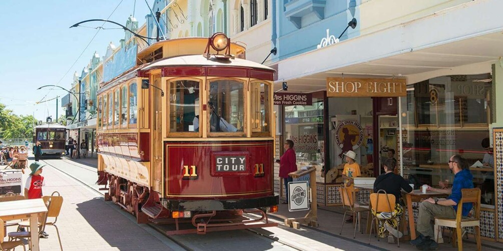 A vintage trolley labeled 'City Tour' parked on a street with shops and people. 5