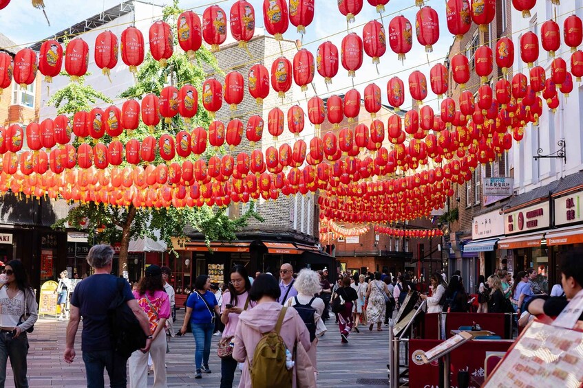 A street decorated with red lanterns and people walking. 3