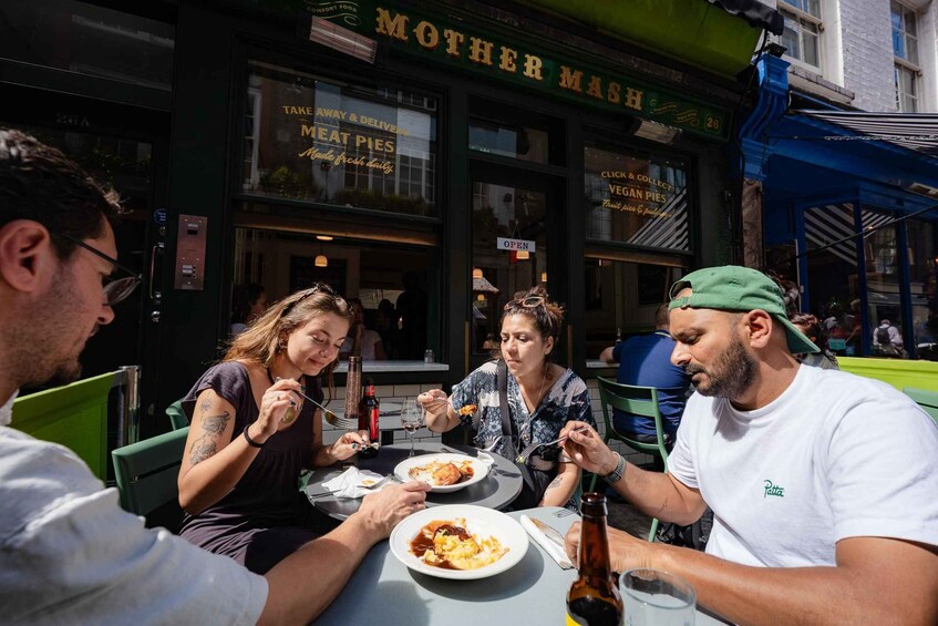 People dining at an outdoor table in front of a restaurant named 'Mother Mash.' 4