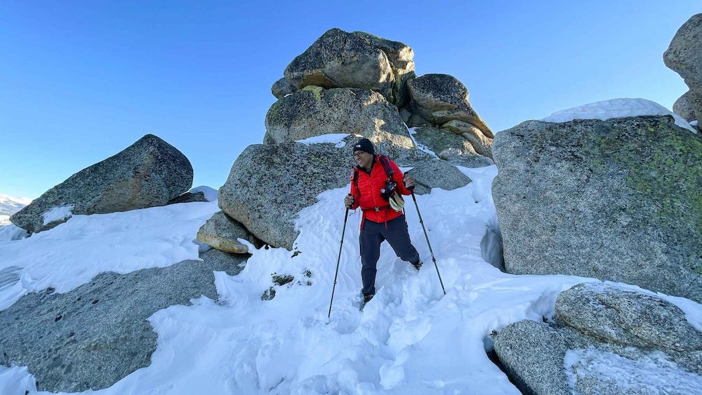 A person hiking in a snowy mountainous area with large rocks. 2