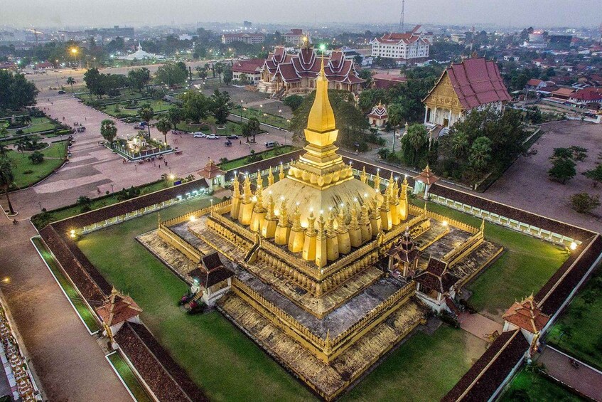 A golden stupa surrounded by a square courtyard with traditional buildings in the background. 3