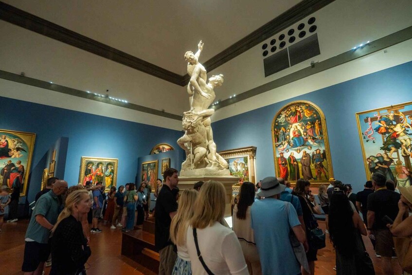 A museum interior with visitors, a large sculpture, and classical paintings. 2
