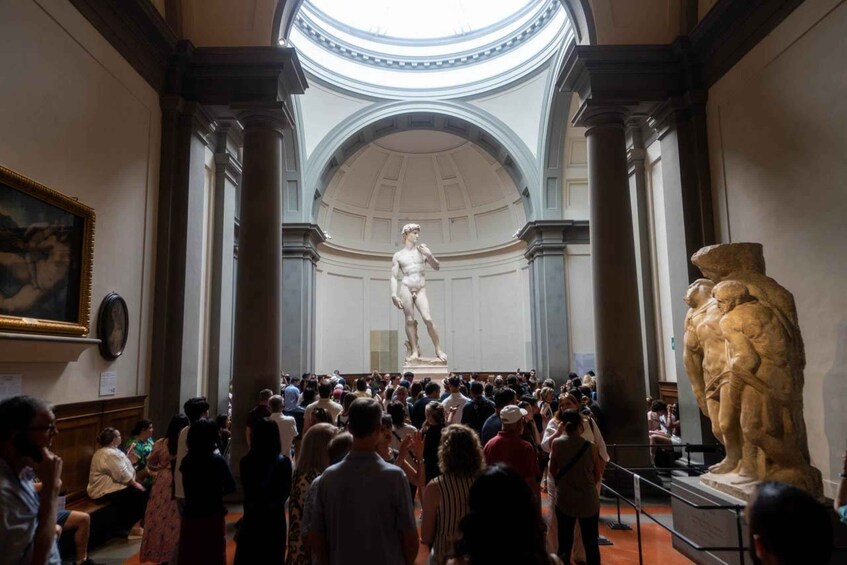 A classical statue in a museum with a crowd of visitors. 5