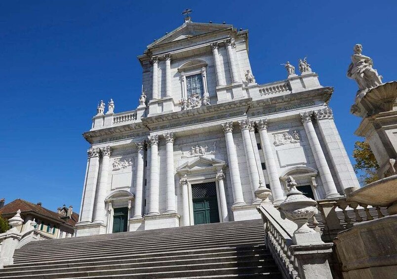 A grand white building with columns and statues, a large entrance, and a staircase leading up to it. 5