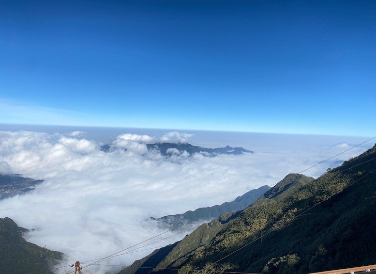 A mountainous landscape with a clear sky, power lines, and a view of the clouds below. 4