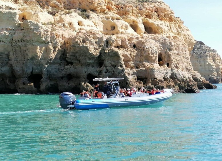 A boat with passengers near rocky cliffs. 3
