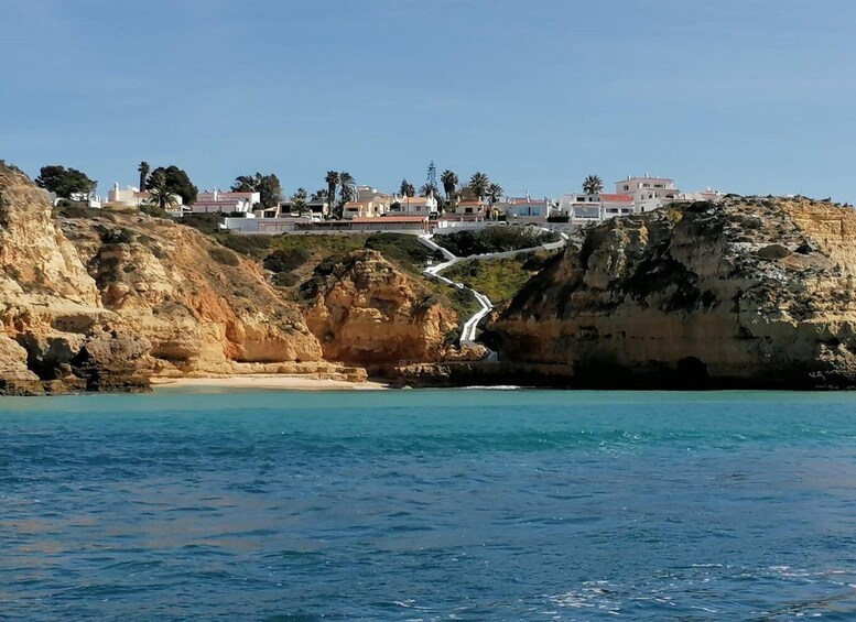 A coastal landscape with a rocky cliff, a winding road, and buildings on the hillside. 4