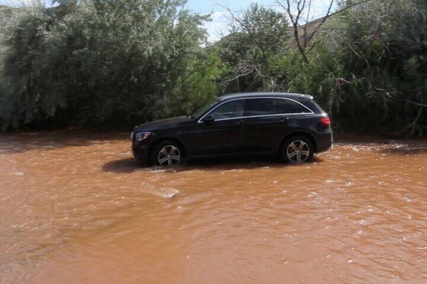 A black SUV partially submerged in muddy water. 4