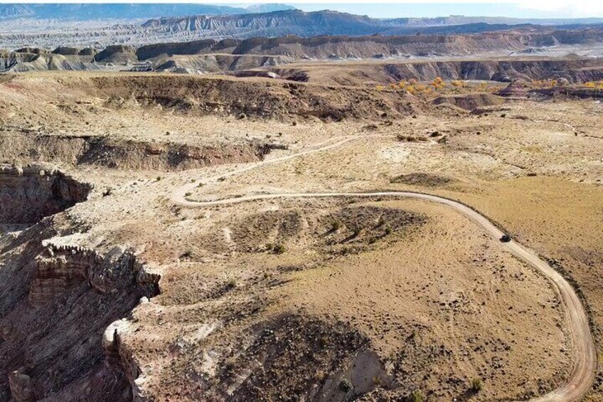 A winding dirt road through a barren landscape with rocky terrain and distant hills. 5