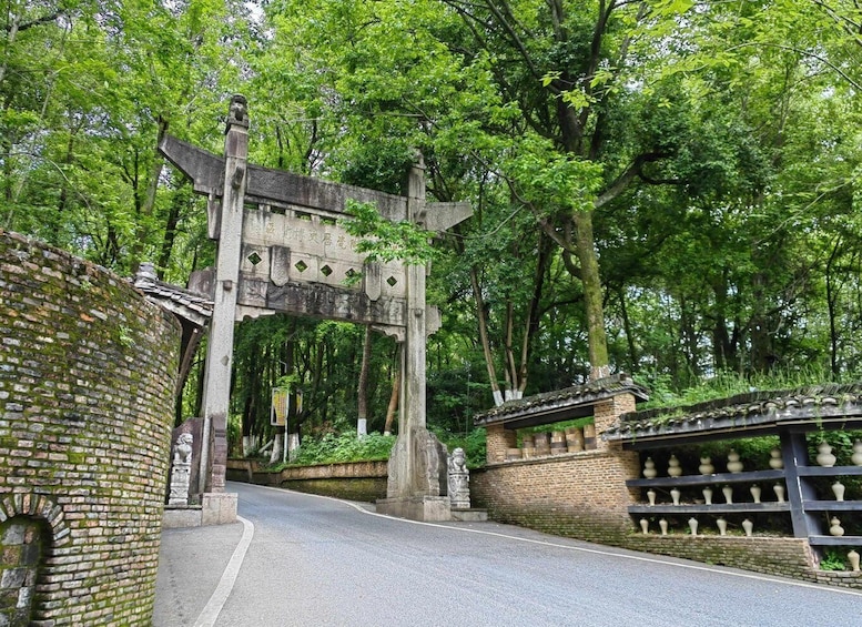 A traditional stone archway with inscriptions, surrounded by lush greenery and a brick wall with decorative elements. 3