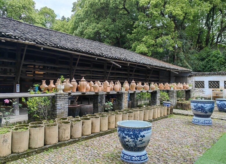A traditional building with a tiled roof, surrounded by various ceramic pots and large blue and white vases. 5
