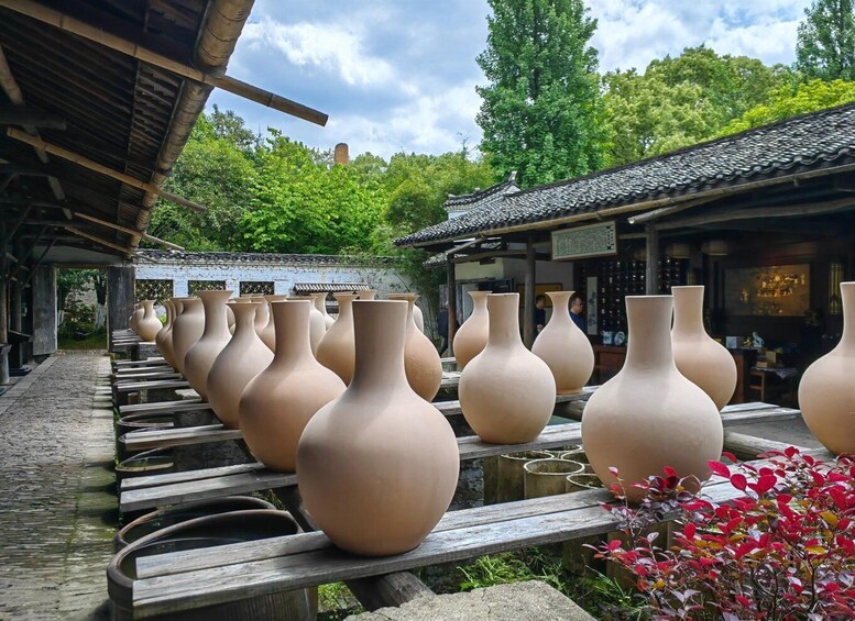 Ceramic vases lined up on wooden benches in a courtyard with traditional architecture. 1
