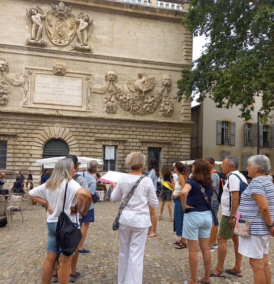A group of people standing in front of a building with ornate carvings and a plaque. 5
