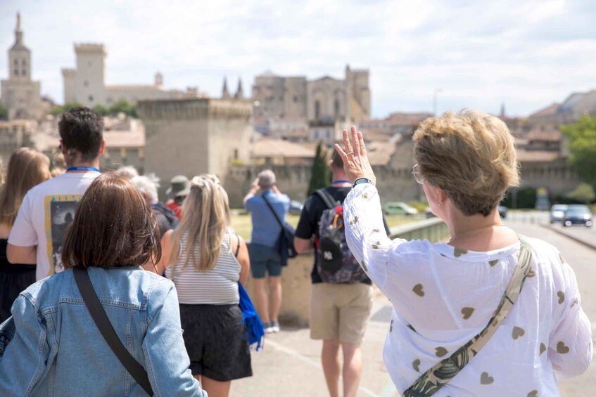 A group of people walking on a bridge with historic buildings in the background. 1