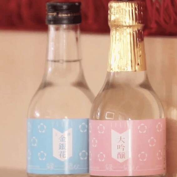 Two bottles with labels, one blue and one pink, against a red background. 3