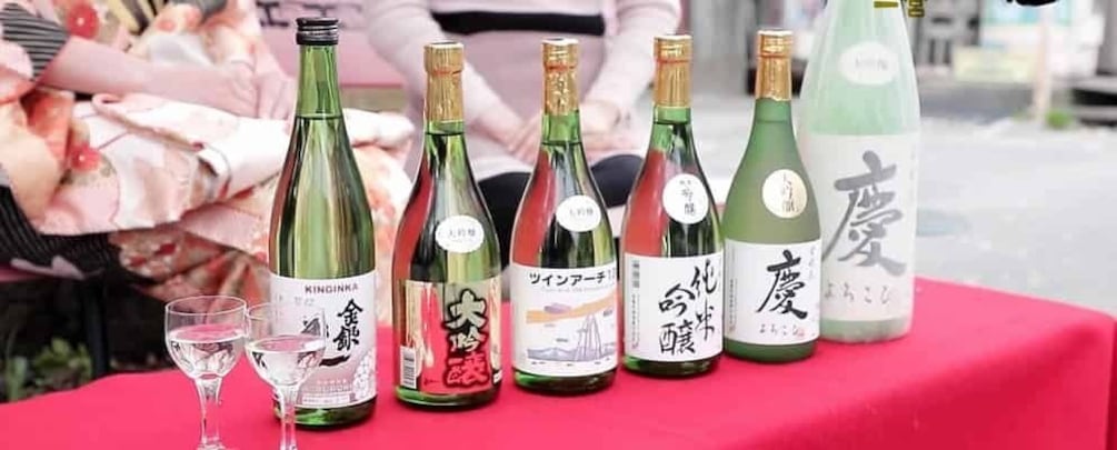 A row of sake bottles on a table with a red tablecloth. 5