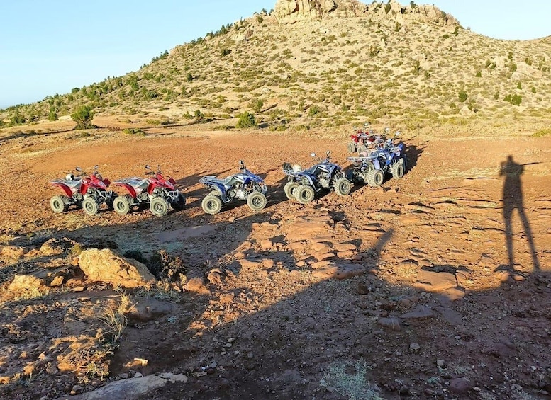 A line of off-road vehicles parked on a rocky terrain with a desert landscape in the background. 5