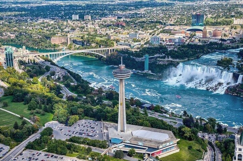 A cityscape with a prominent tower, a waterfall, and a bridge. 2
