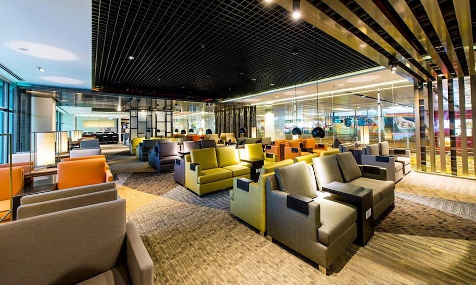A modern lounge area with sofas and chairs, a patterned carpet, and a ceiling with a grid design. 5