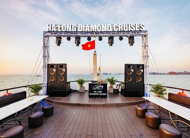A deck with a stage, speakers, and a flag, overlooking a body of water. 4