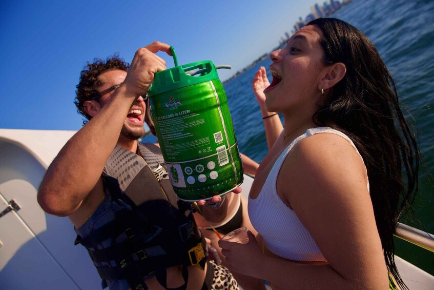 Two people on a boat holding a green Heineken can. 3