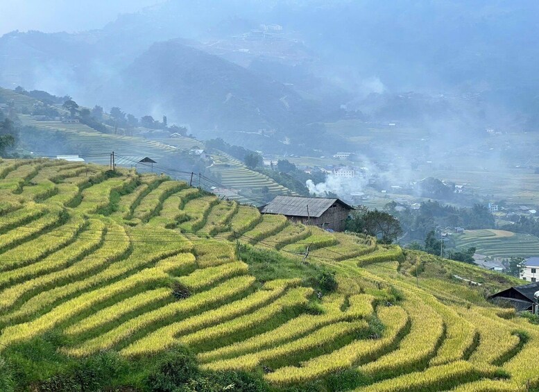 Terraced rice fields, a small traditional house, and distant smoke from a chimney. 2