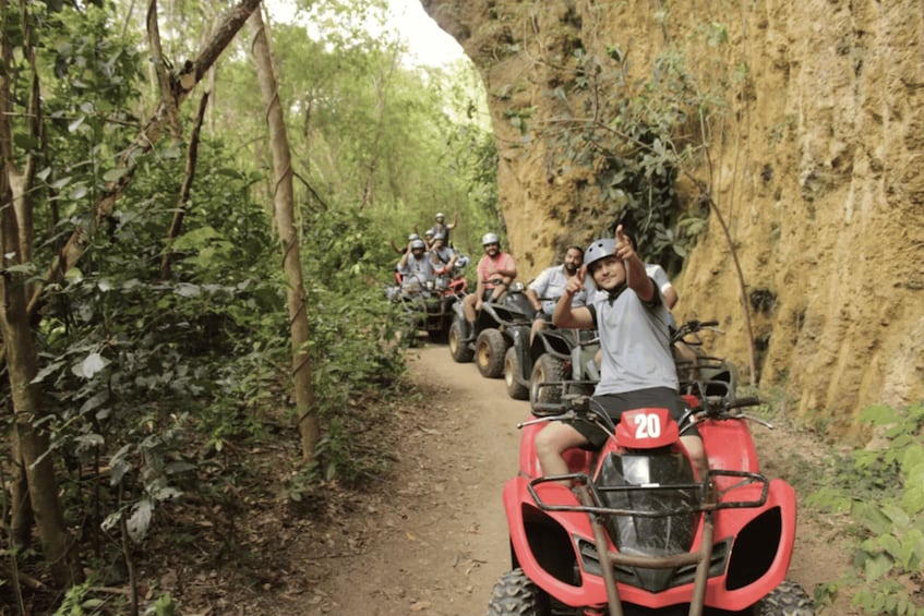 A group of people on ATVs on a narrow forest trail. 4