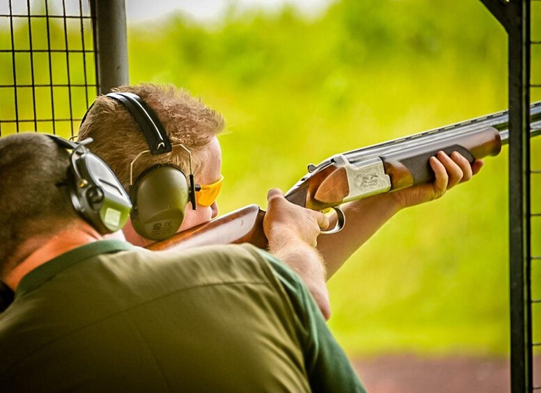A person aiming a shotgun with ear protection. 1