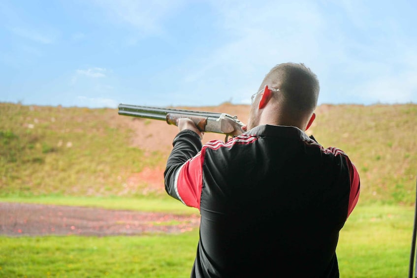 A person aiming a shotgun at a target. 3