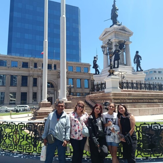 A group of people posing in front of a monument with statues and a building in the background. 4