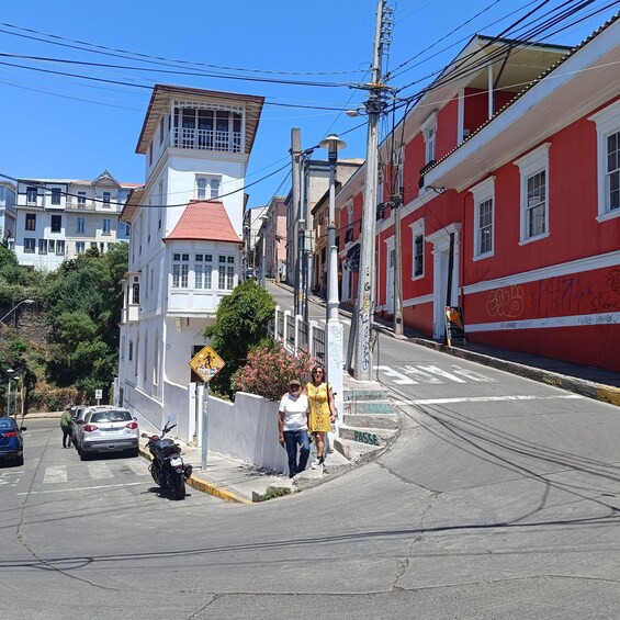 A street with buildings, a pedestrian crossing, and parked cars. 5