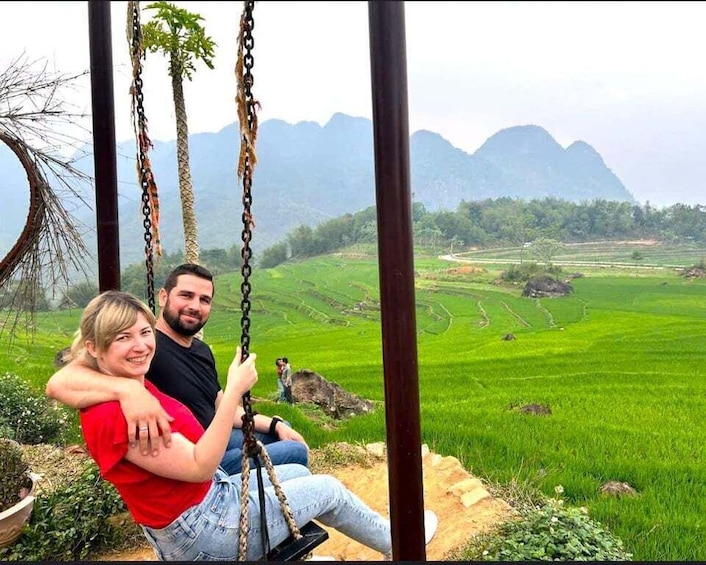 A couple on a swing overlooking a terraced rice field with mountains in the background. 4
