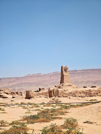 A desert landscape with a prominent rock formation and sparse vegetation. 2