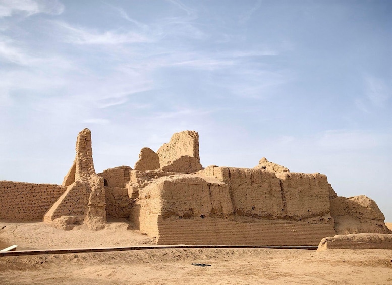 Ancient mud-brick ruins with stepped structures and a flat-topped building. 5