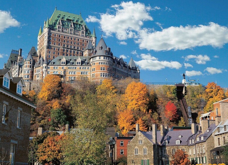 A historic castle with a green roof, surrounded by autumn-colored trees and traditional buildings. 1