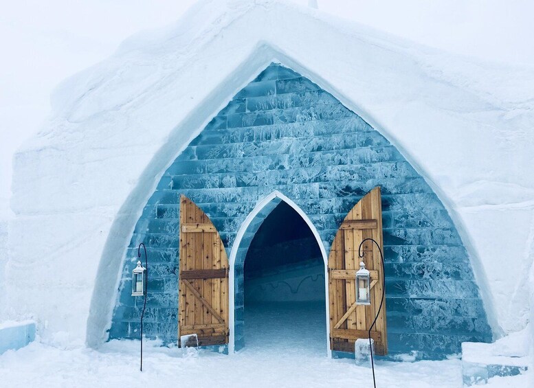 An ice igloo entrance with wooden doors and lanterns. 5