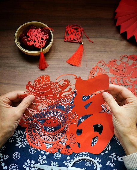 Hands assembling red paper cut-out decorations. 5