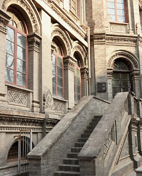 A historic building with ornate architectural details, including a grand staircase leading to a large arched doorway. 1