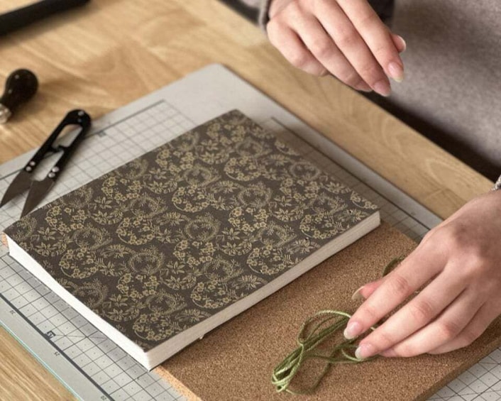 A person cutting a patterned book with scissors on a cutting mat. 2
