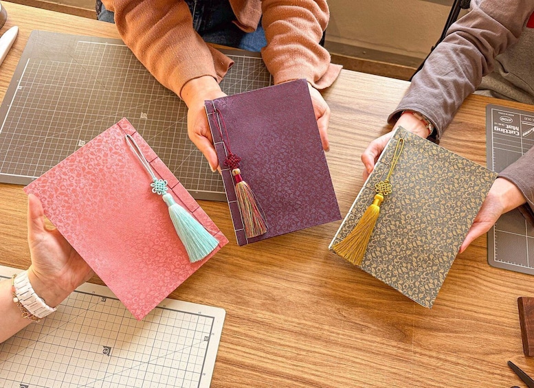 Three notebooks with tassels on a wooden table. 1