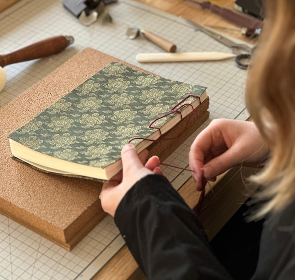 A person repairing a book with a green cover. 5