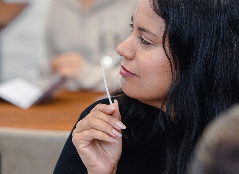 A person holding a white object, possibly a pen or marker, in a casual indoor setting. 2