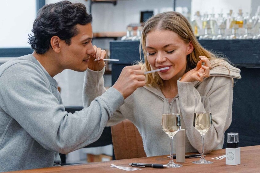 Two people sitting at a table with wine glasses and a small box. 1