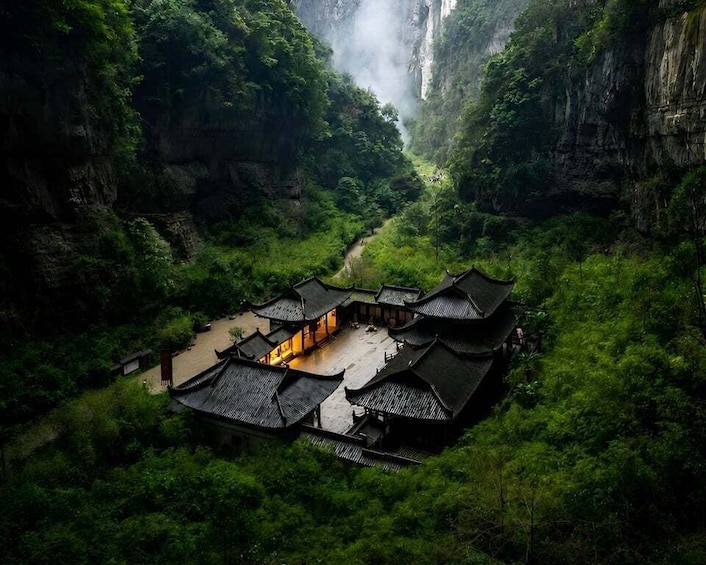 A traditional Chinese courtyard surrounded by lush greenery and a waterfall. 1