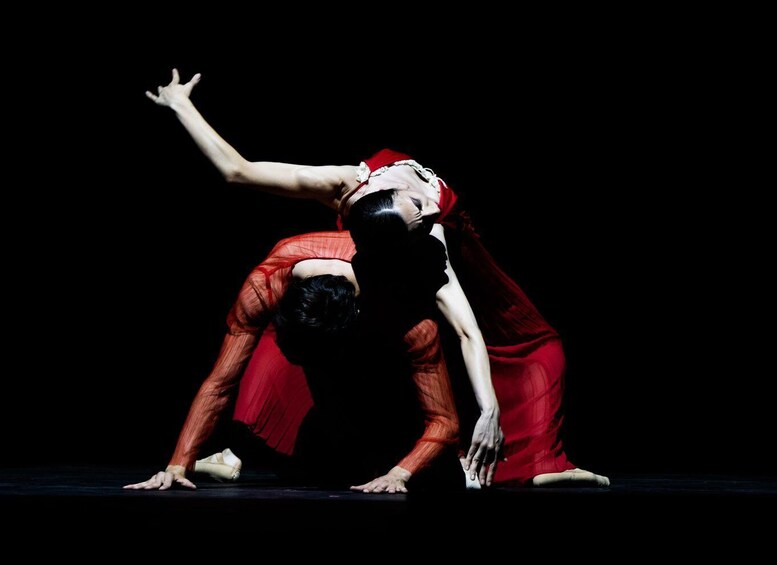 A dancer in red performing a low, bent-over pose on a stage. 5