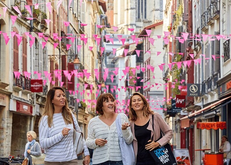 A street with buildings, pink triangular flags, and a sign that reads 'DINO STAY SERIOUS.' 5