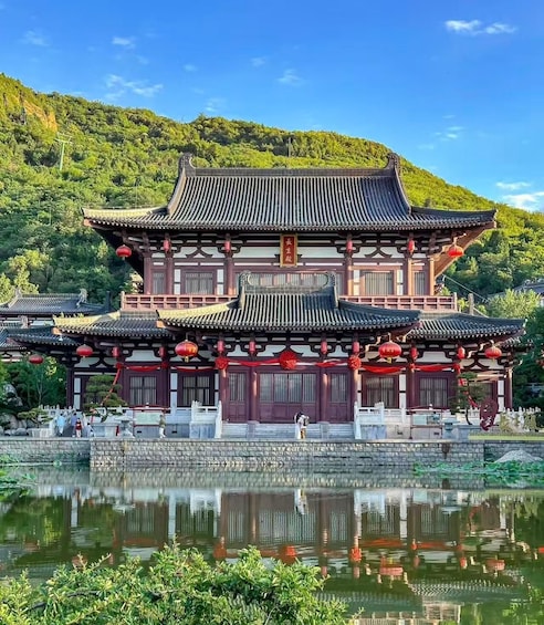 A traditional Chinese building with a reflection in the water, surrounded by greenery and hills. 1