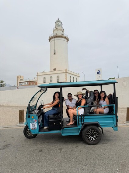 A turquoise golf cart with five passengers, a white lighthouse in the background, and a sign indicating a parking area. 3