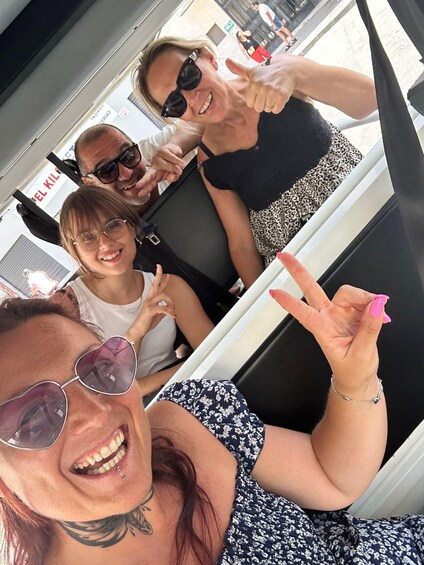 Three people inside a vehicle, with one giving a thumbs-up. 1